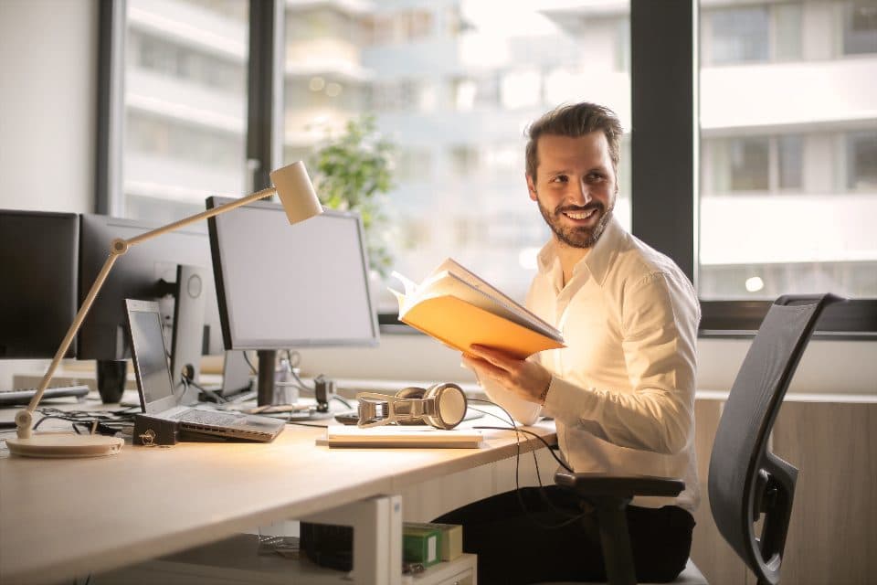 Gestor sorrindo enquanto lê documentos em seu escritório